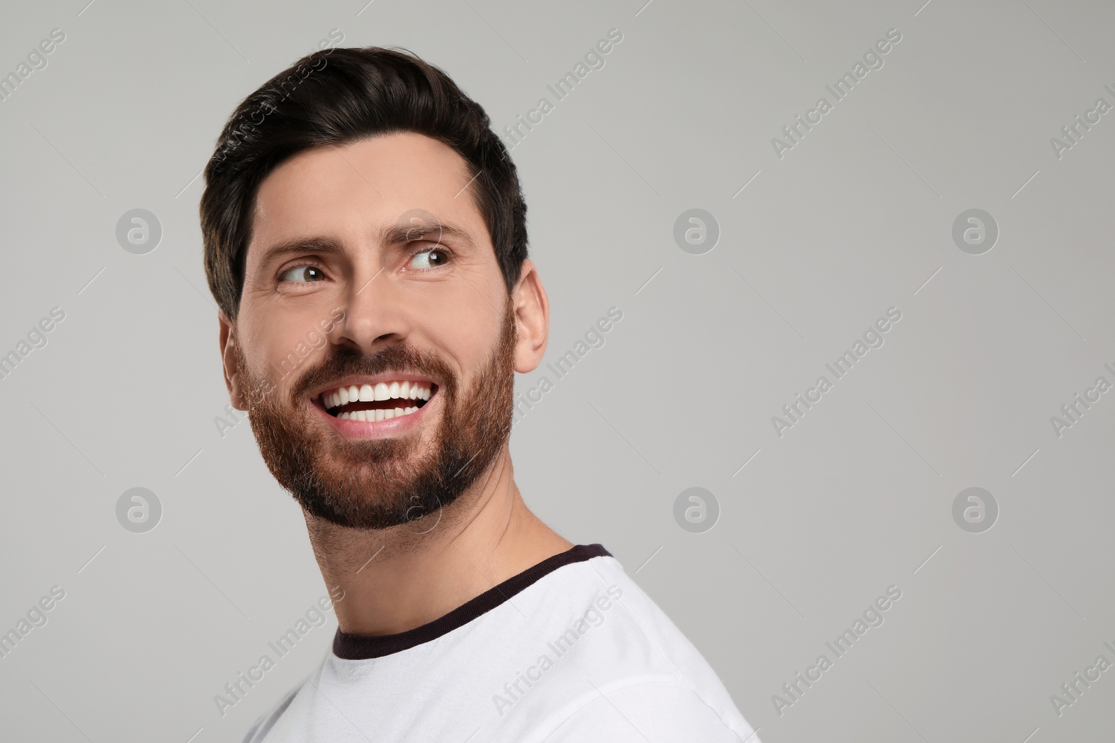 Photo of Portrait of smiling man with healthy clean teeth on light grey background. Space for text