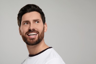 Photo of Portrait of smiling man with healthy clean teeth on light grey background. Space for text