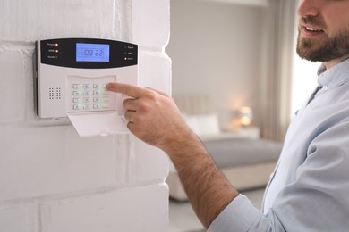 Photo of Man entering code on security alarm system at home, closeup