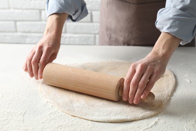 Photo of Woman rolling raw dough at table, closeup