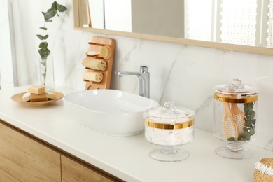 Jars with cotton pads and hairbrushes on bathroom countertop