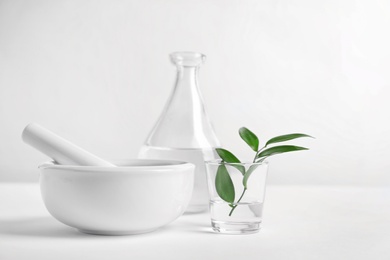 Photo of Composition with mortar and pestle on table against light background. Homemade cosmetic products