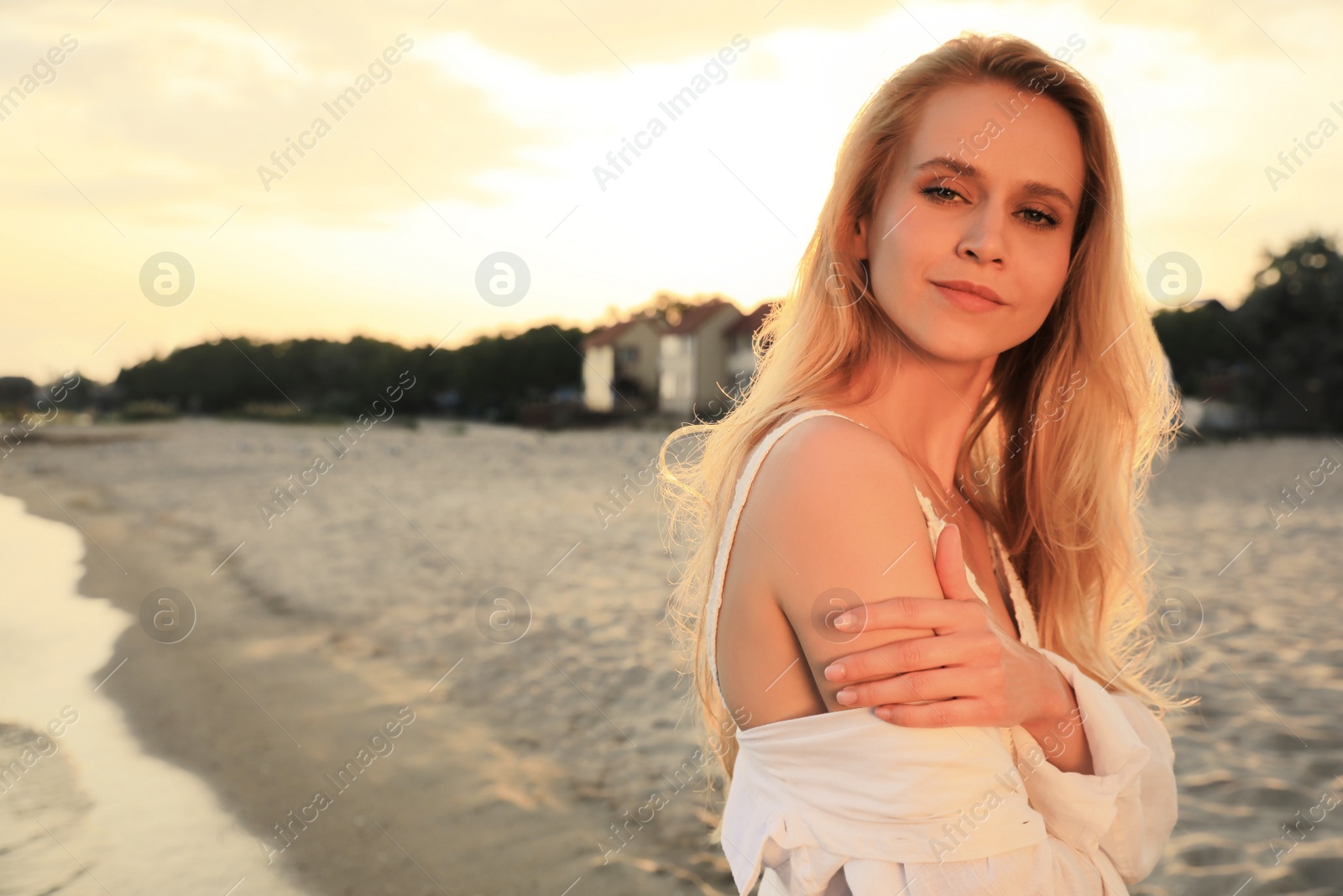 Photo of Beautiful young woman on beach at sunset, space for text