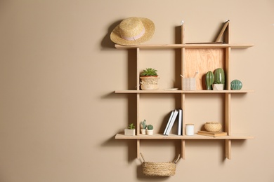 Photo of Wooden shelves with different decorative elements on beige wall, space for text