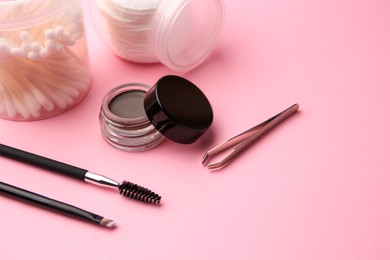 Photo of Eyebrow pomade with henna effect and professional tools on pink background