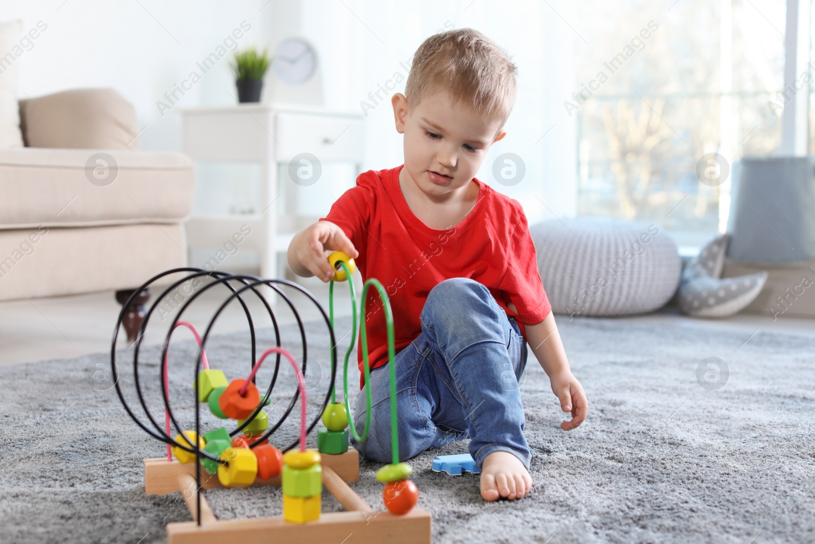 Photo of Cute child playing with bead maze on floor indoors