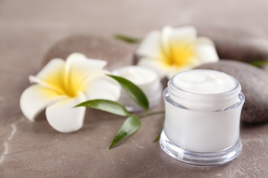 Beautiful composition with cream, spa stones and flowers on table, closeup. Space for text