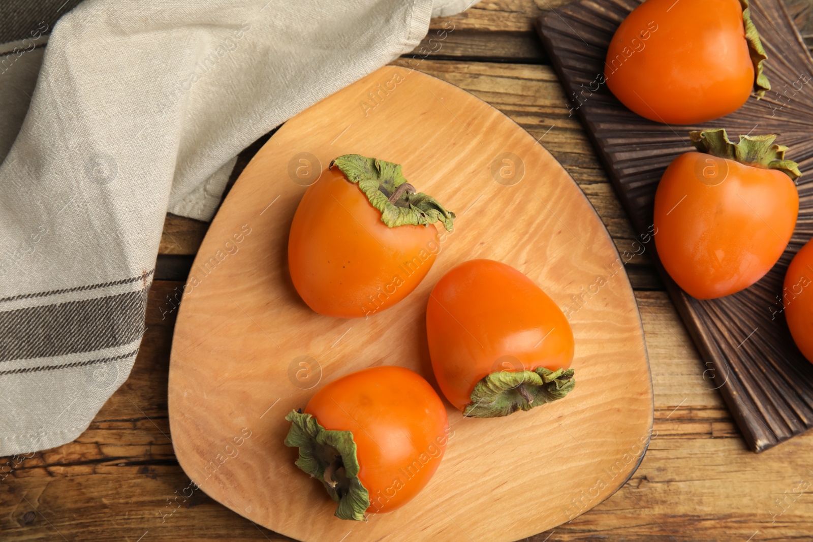 Photo of Tasty ripe persimmons on wooden table, flat lay