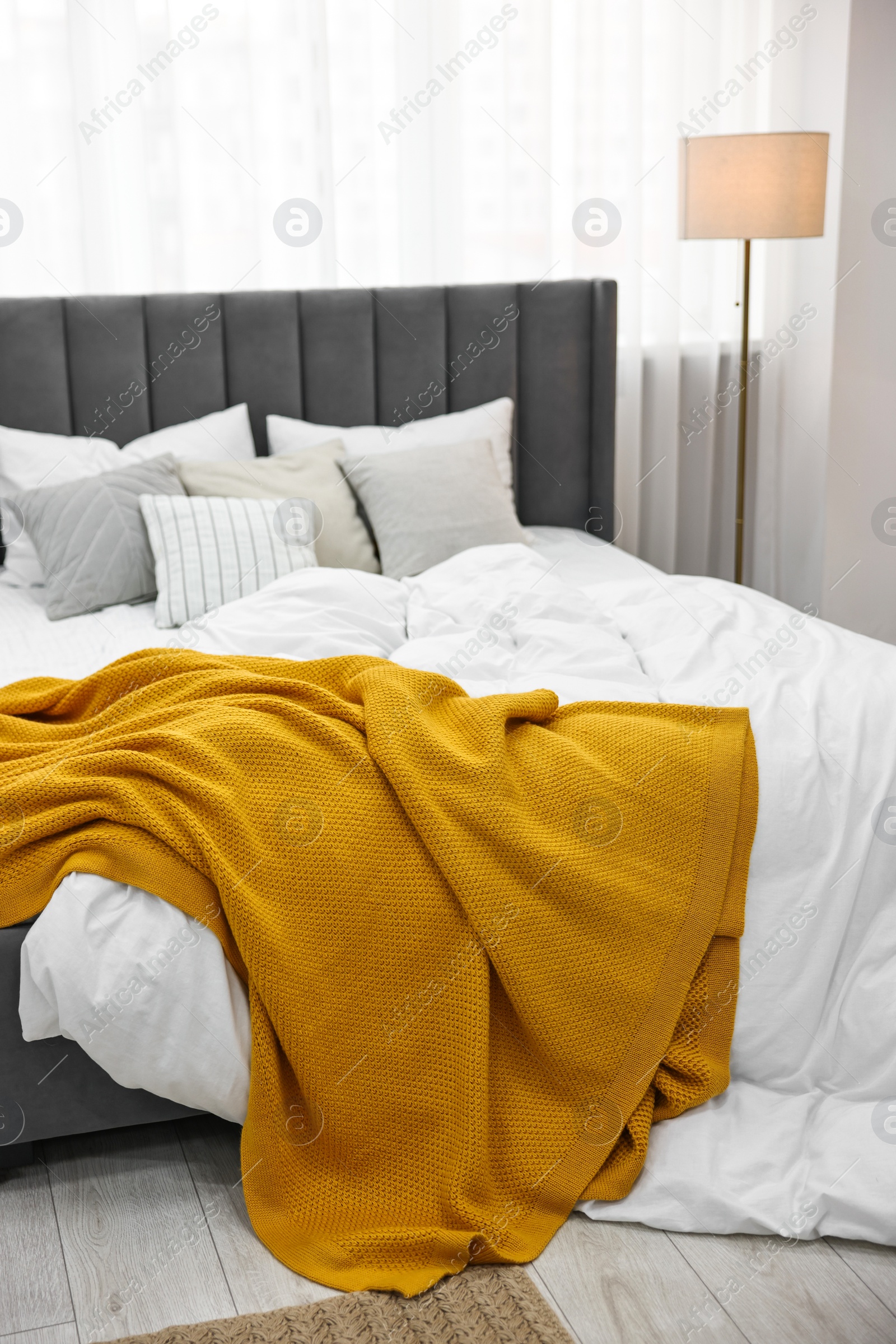 Photo of Bright plaid on bed in stylish bedroom