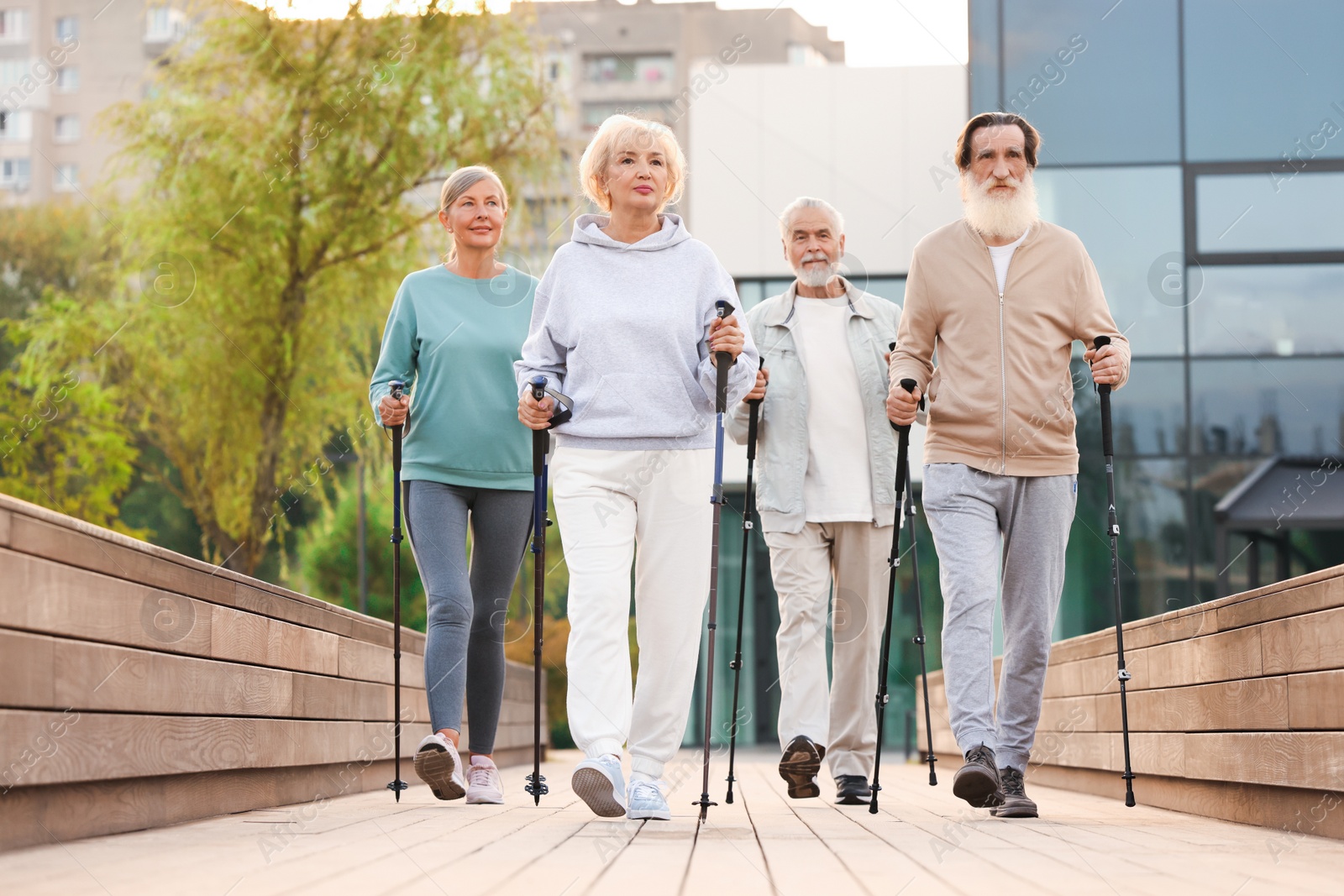 Photo of Group of senior people performing Nordic walking outdoors. Low angle view