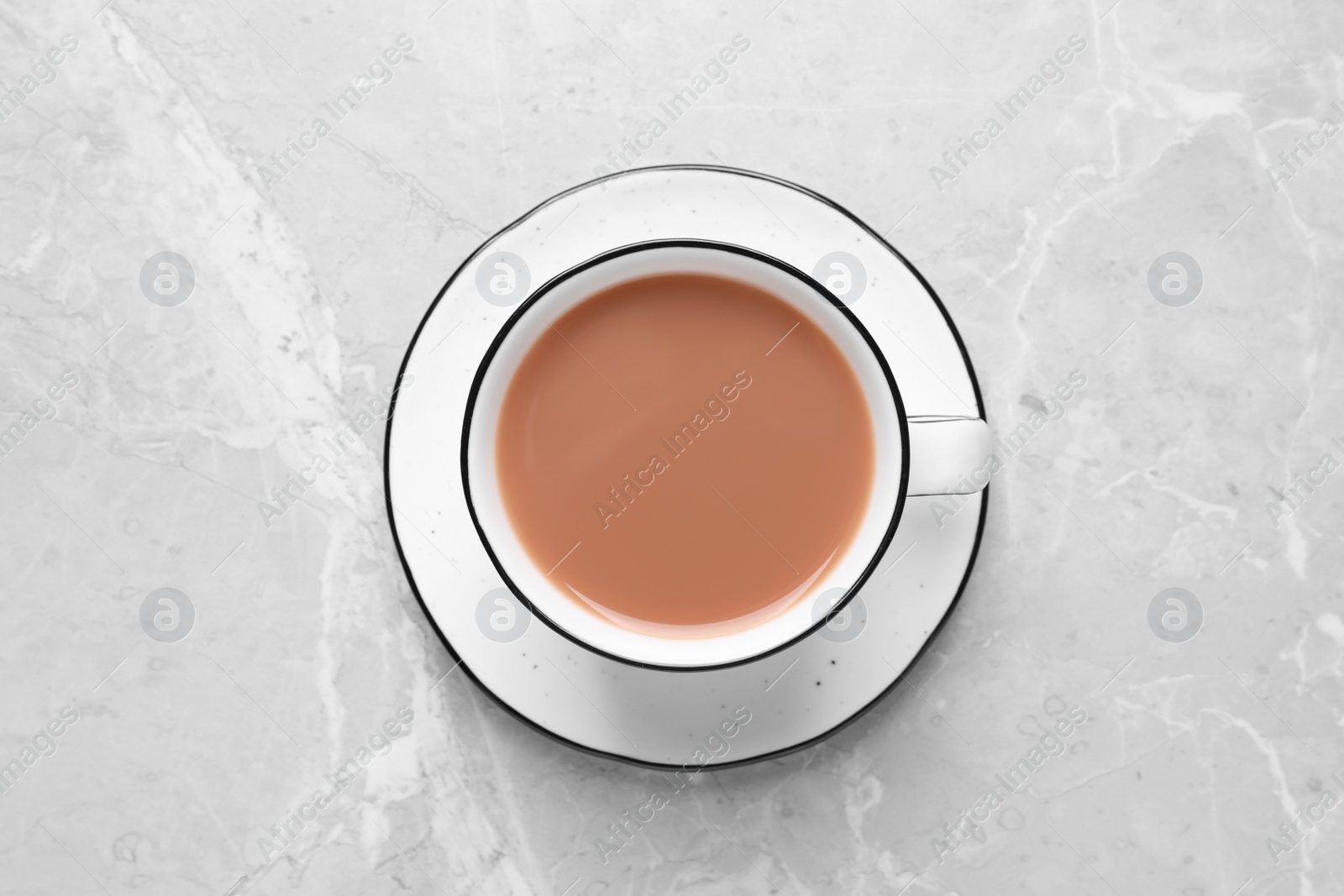 Photo of Delicious tea with milk in white cup on grey table, top view