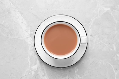 Delicious tea with milk in white cup on grey table, top view