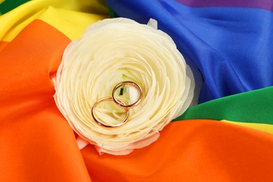 Photo of Wedding rings and flower on rainbow LGBT flag, closeup