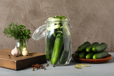 Photo of Pickling jar with fresh ripe cucumbers on grey wooden table