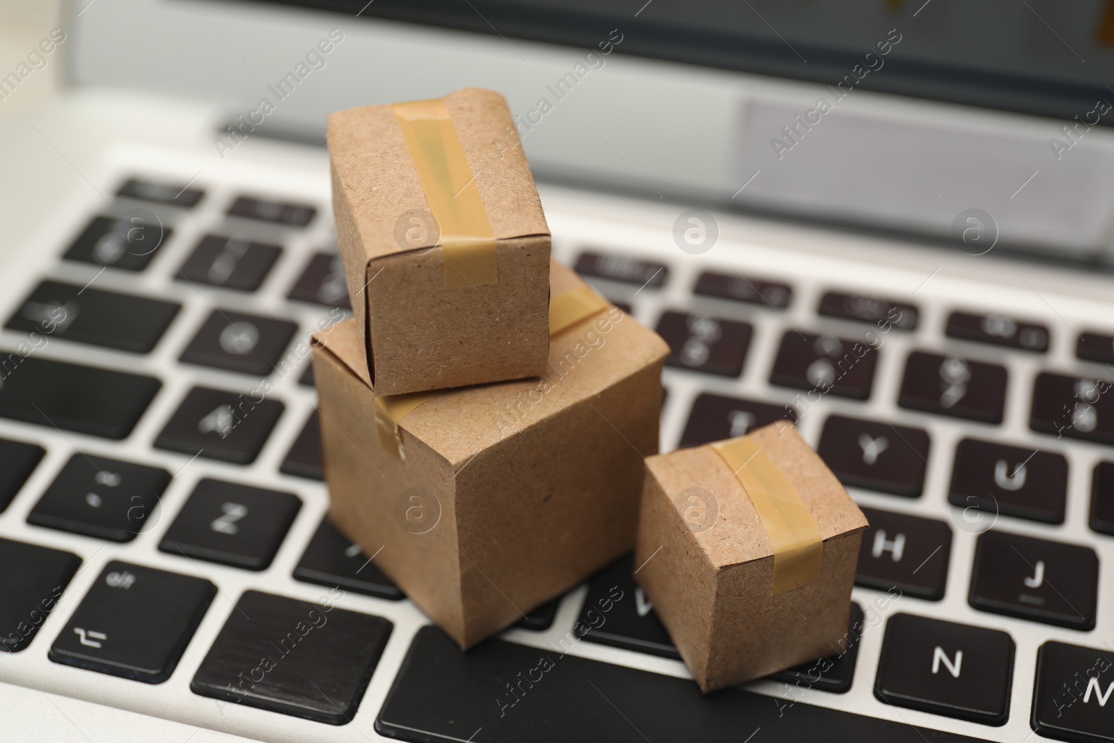 Photo of Internet shopping. Small cardboard boxes on laptop, closeup