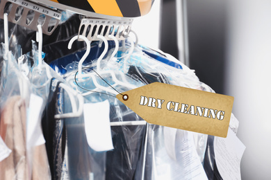 Image of Hangers with clothes on garment conveyor at dry-cleaner's, closeup