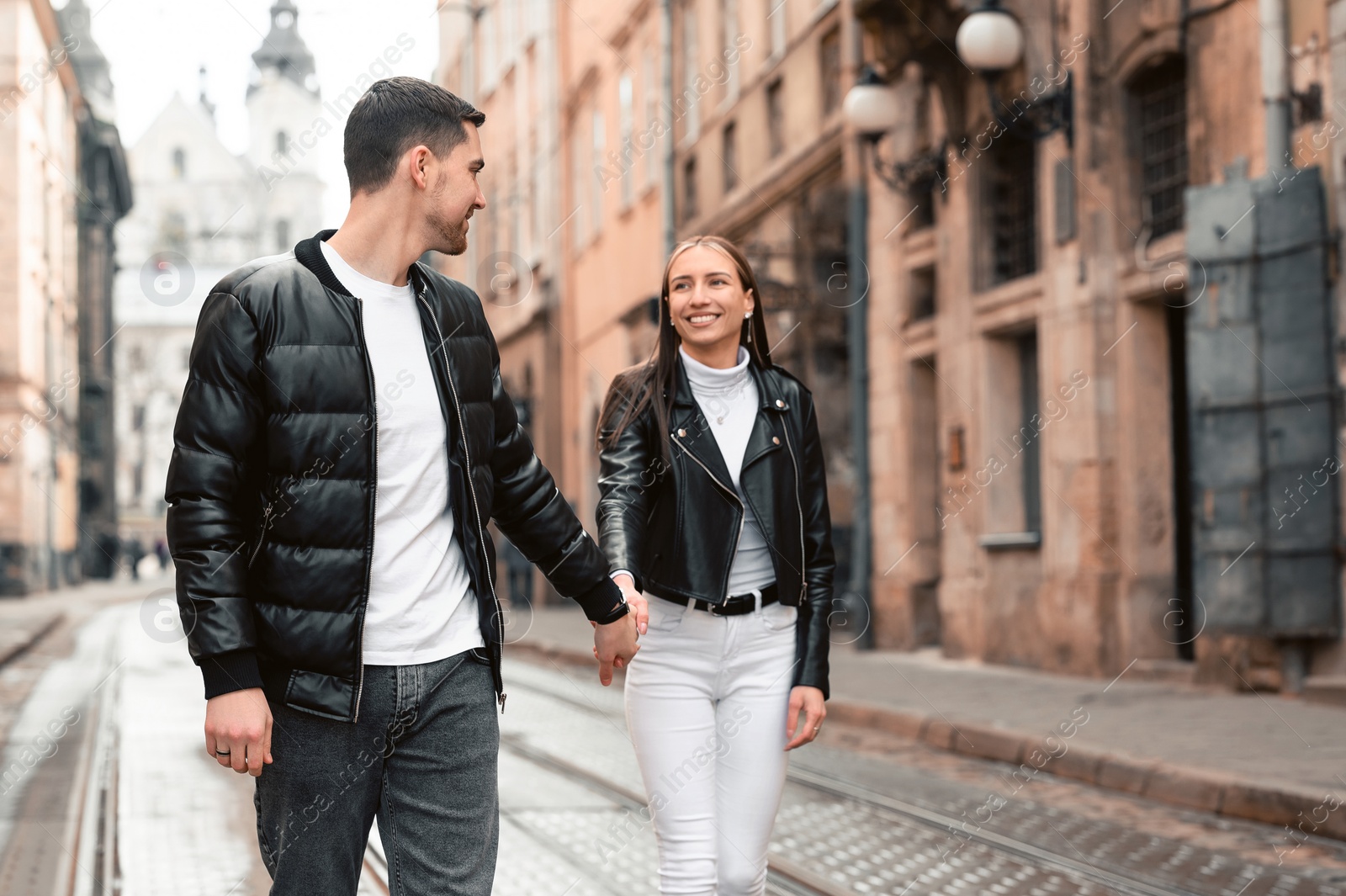 Photo of Lovely young couple walking along tram track on pavement road. Romantic date