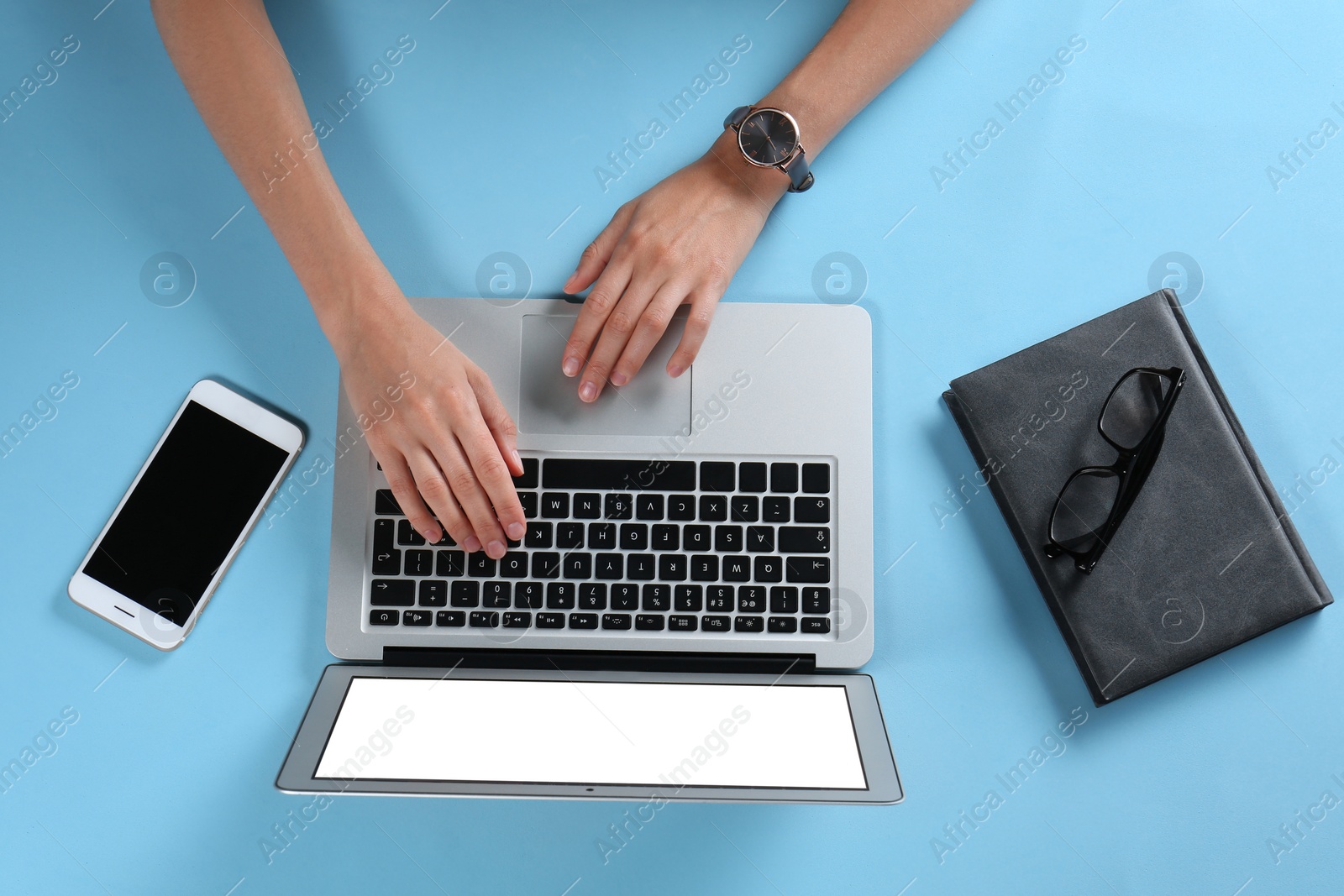 Photo of Young woman using laptop on light blue background, top view