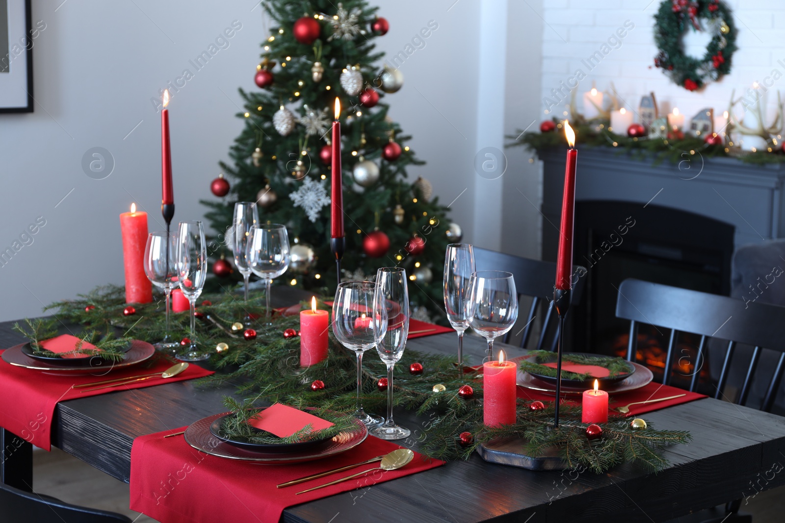 Photo of Elegant Christmas table setting with dishware and burning candles in festively decorated room