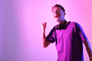 Photo of Young man having fun on pink background in neon lights. Space for text