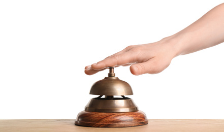 Photo of Woman ringing hotel service bell at wooden table