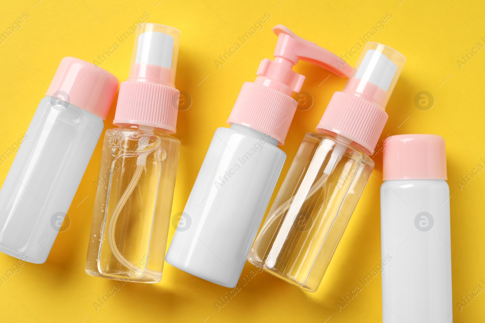 Photo of Cosmetic travel kit on yellow background, flat lay. Bath accessories