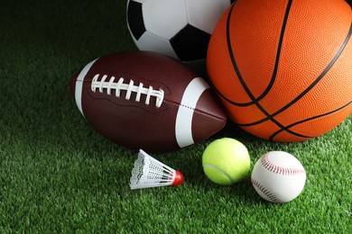 Set of different sport balls and shuttlecock on green grass