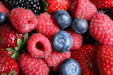 Mix of different ripe tasty berries as background, top view