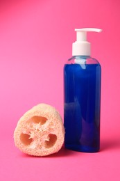Photo of Natural loofah sponge and bottle of cosmetic product on pink background