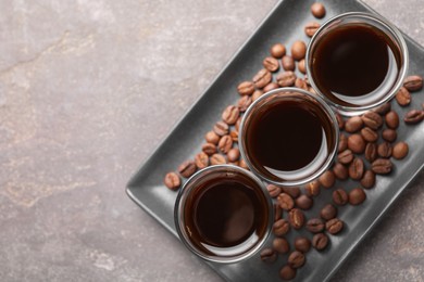Shot glasses with coffee liqueur and beans on light grey table, top view. Space for text