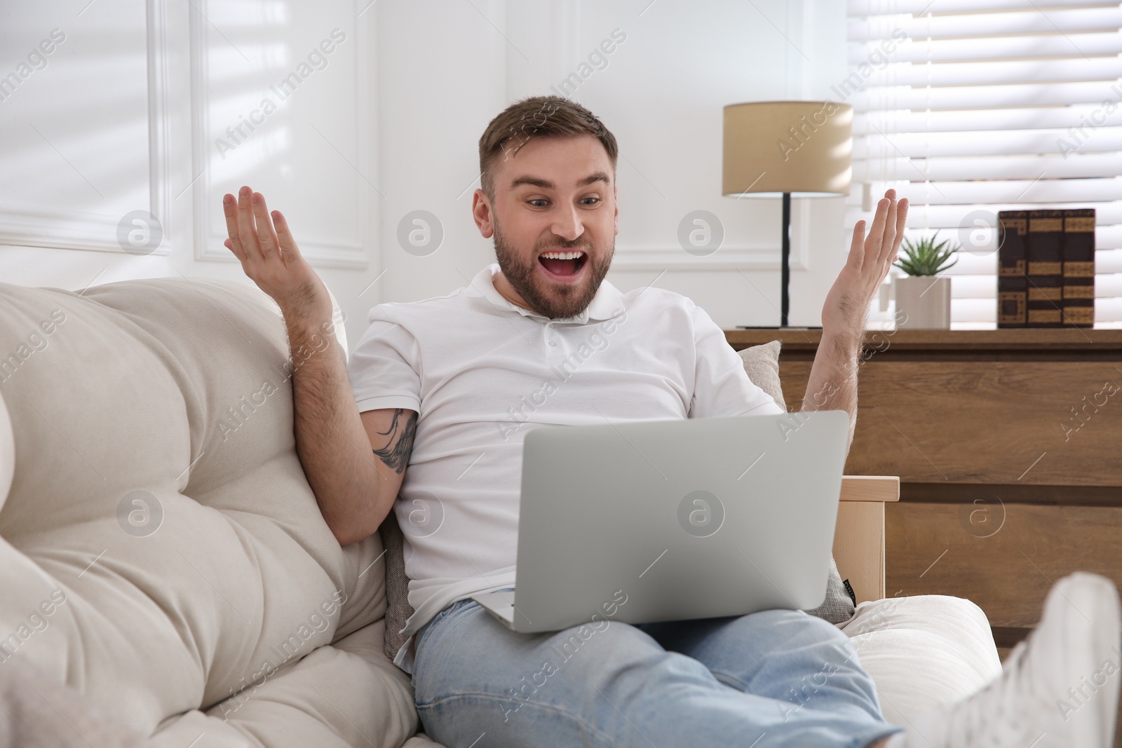 Photo of Emotional man participating in online auction using laptop at home