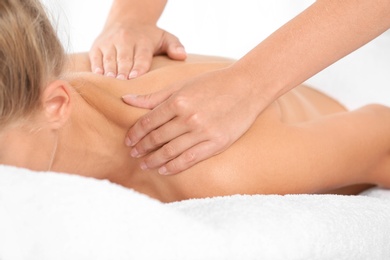 Photo of Relaxed woman receiving shoulders massage in wellness center