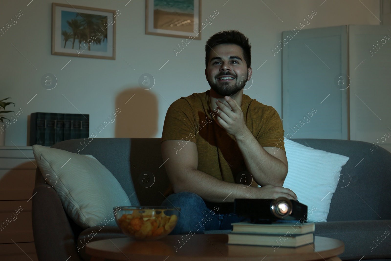 Photo of Young man watching movie using video projector at home