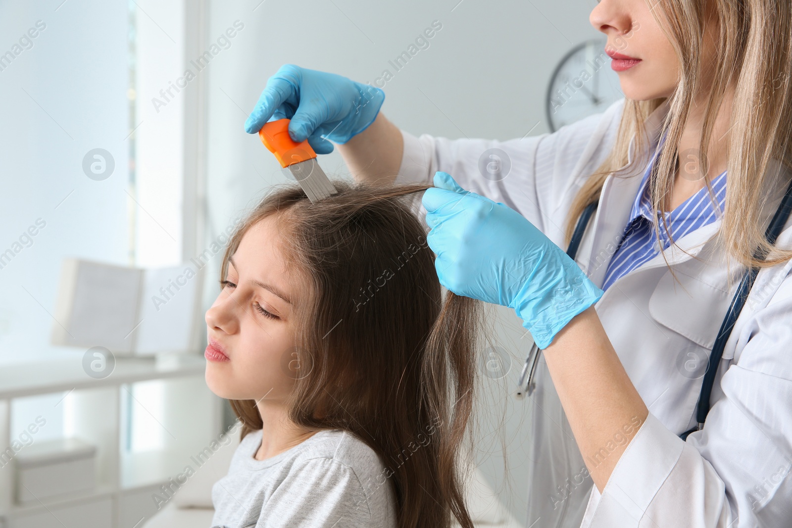 Photo of Doctor using nit comb on girl's hair in clinic. Anti lice treatment