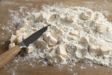 Photo of Making shortcrust pastry. Flour, butter and knife on wooden table