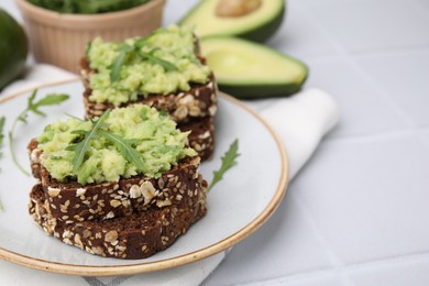 Photo of Delicious sandwiches with guacamole and arugula on white table, closeup
