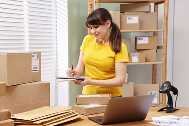 Photo of Parcel packing. Post office worker writing notes indoors