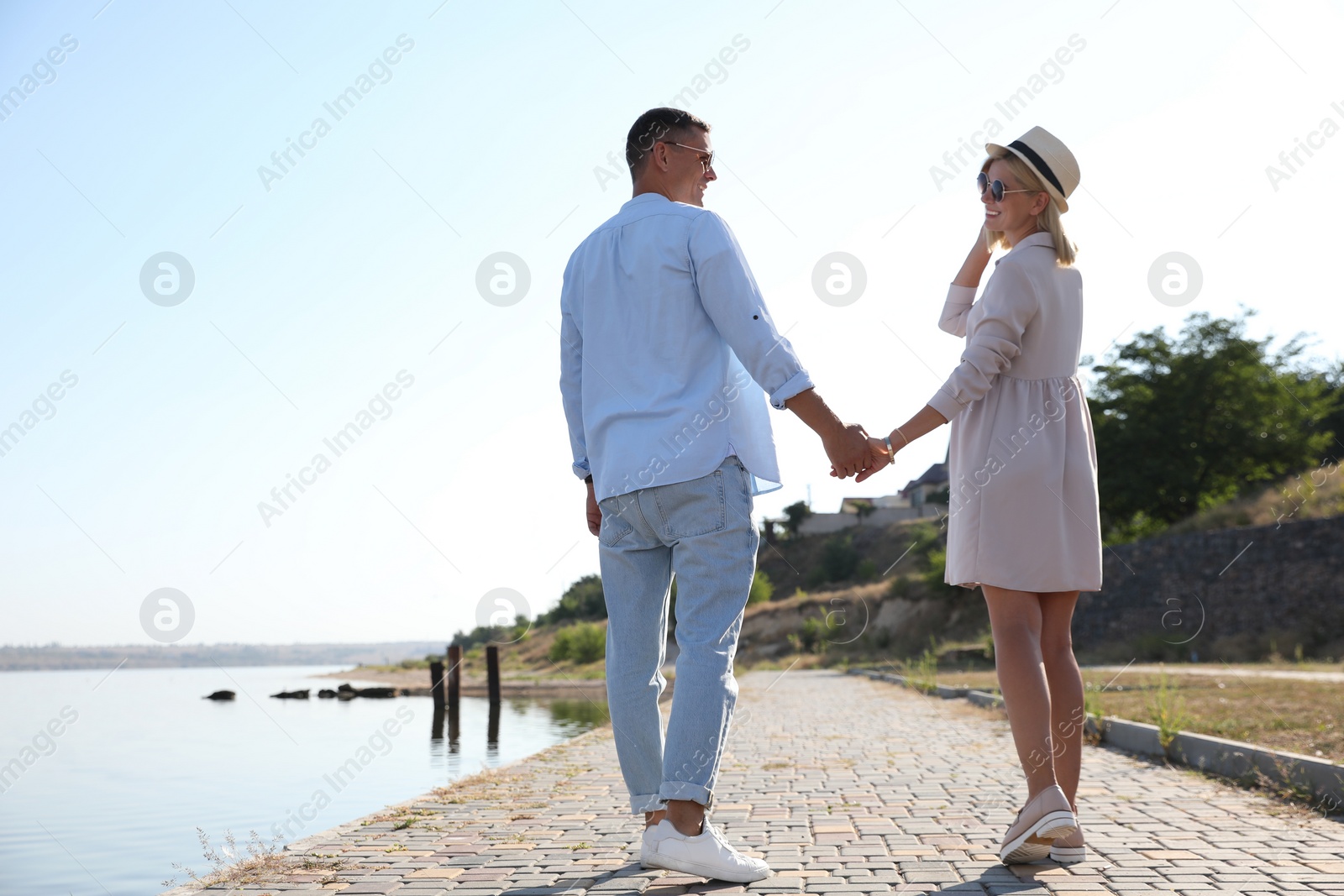 Photo of Happy couple walking along waterfront on summer day