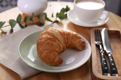 Photo of Tasty croissant served on wooden table, closeup