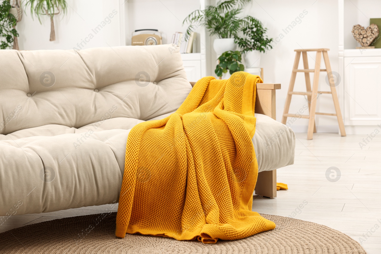 Photo of Comfortable sofa with orange blanket in living room