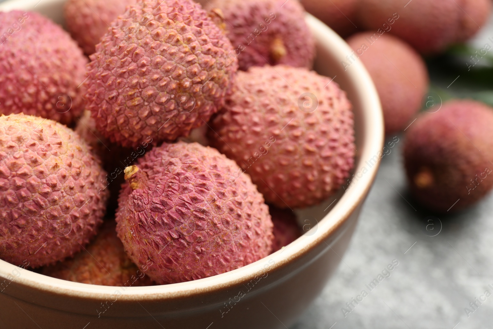 Photo of Fresh ripe lychee fruits in bowl on table, closeup
