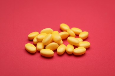 Photo of Many yellow dragee candies on red background