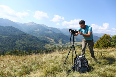 Photographer with backpack, camera and tripod surrounded by breathtakingly beautiful nature