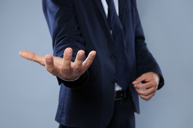 Photo of Businessman holding something on grey background, closeup of hands