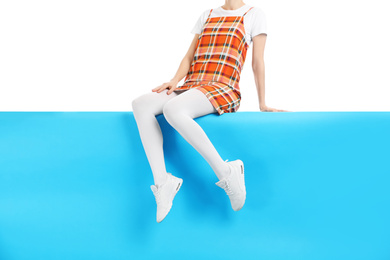 Woman wearing white tights and stylish shoes sitting on color background, closeup