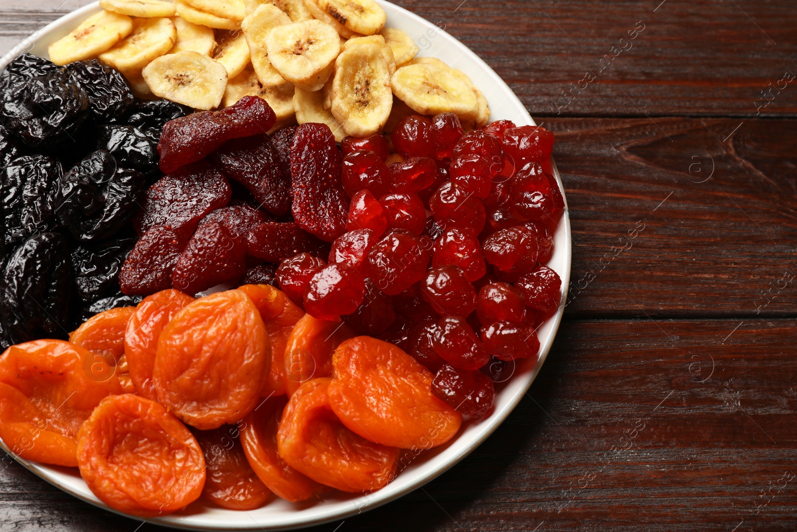 Photo of Delicious dried fruits on wooden table, closeup. Space for text