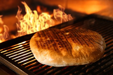 Photo of Baking pita bread on grilling grate in oven, closeup