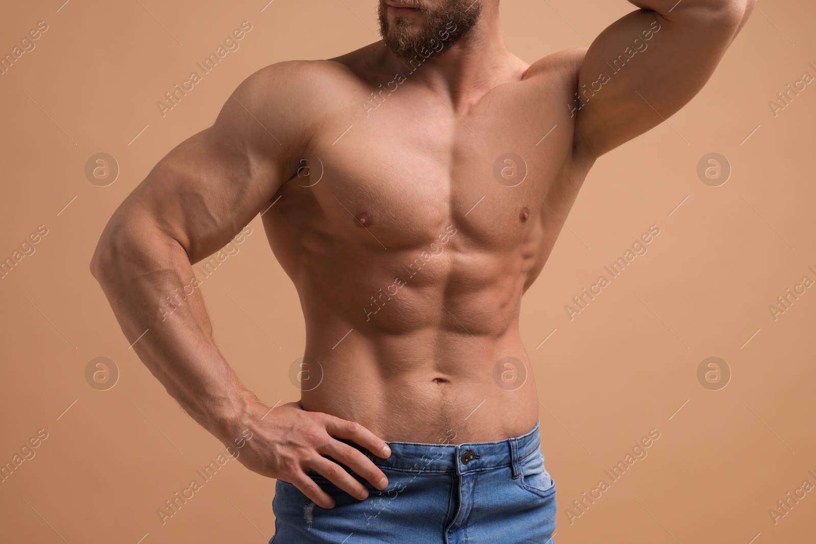 Photo of Muscular man showing abs on beige background, closeup. Sexy body