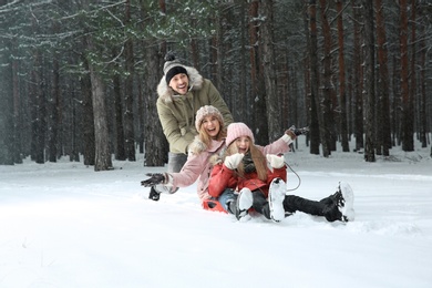 Photo of Happy family sledding in forest on snow day