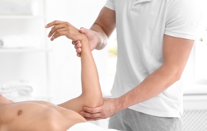 Photo of Young man receiving massage in salon, closeup